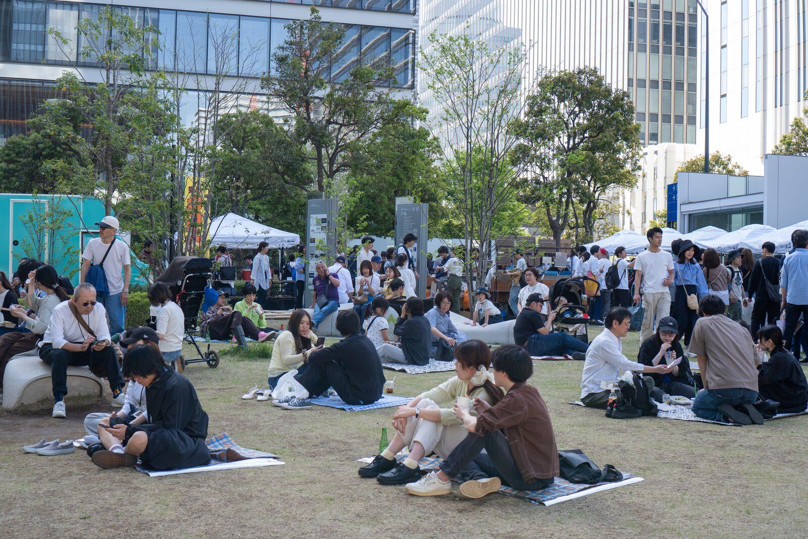 芝生でくつろぐ来場者と会場のテント